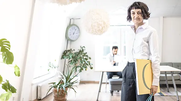 [Translate to Englisch:] Elitsa Pavlova hält ein Canvas und Pinsel in der Hand im Büro.